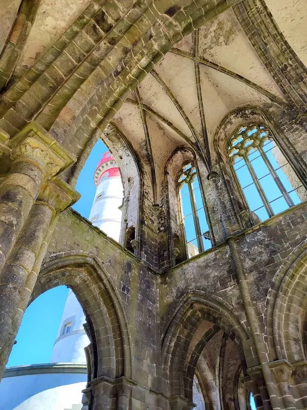 view of a lighthouse through the ruins of a church in Brittany
