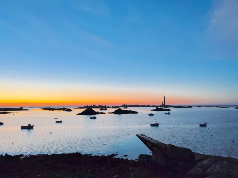 Sunset in Brittany with a lighthouse in the distance on the horizon
