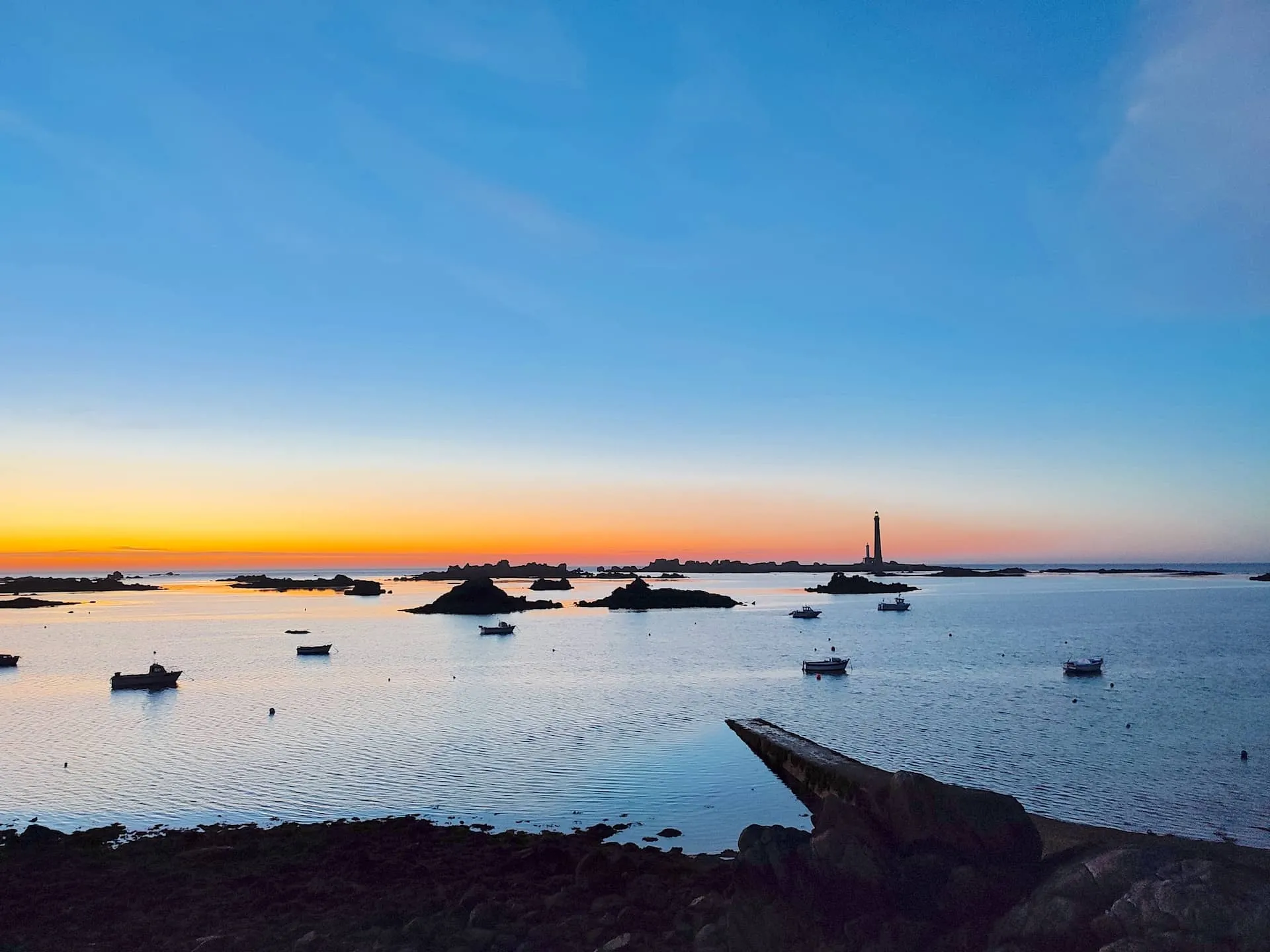 Sunset in Brittany with a lighthouse in the distance on the horizon
