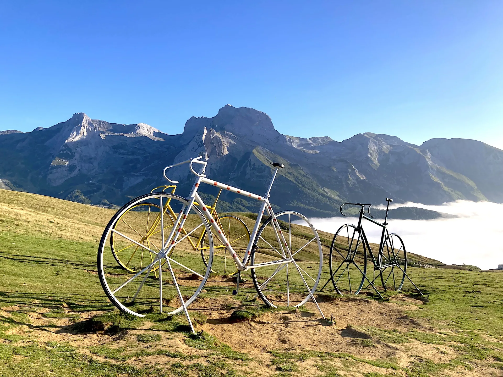 Giant bicycles from the Tour de France at the summit of the Col d'Aubisque in the Pyrenees with sunlit peaks and a sea of clouds