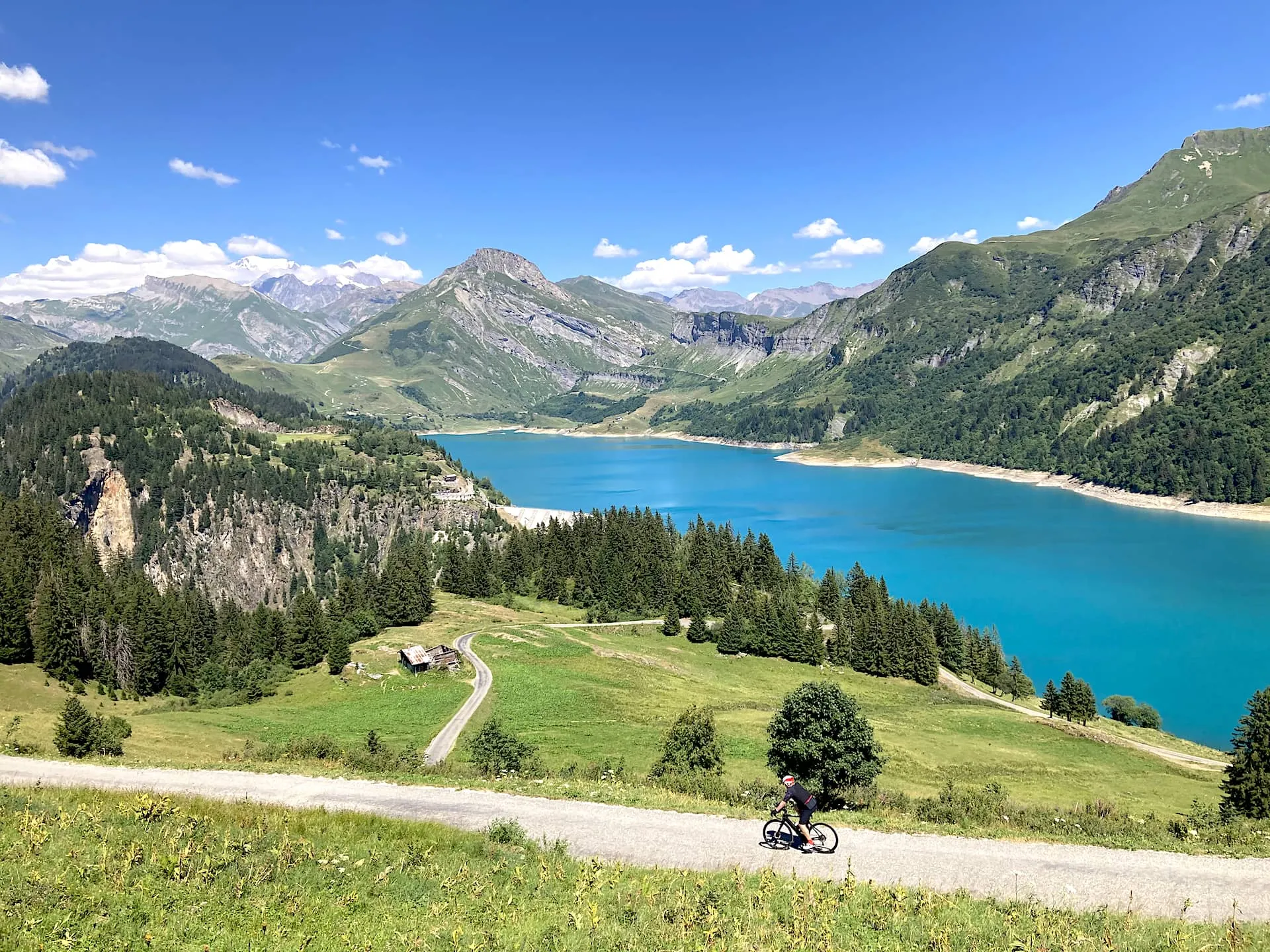 A cyclist traveling with Veymont Travel descending the Col du Pré toward the Roselend Dam and the Col du Cormet Roselend in the Alps