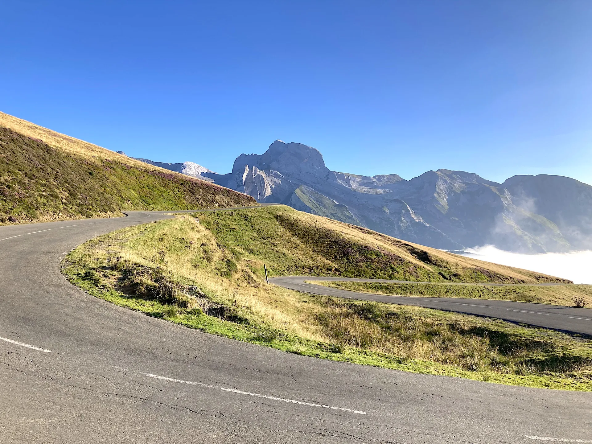 Mountain landscape in the Pyrenees with a winding road between the sun and a sea of clouds