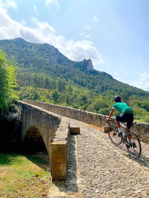 cyclist crossing a stone bridge in Cathar country